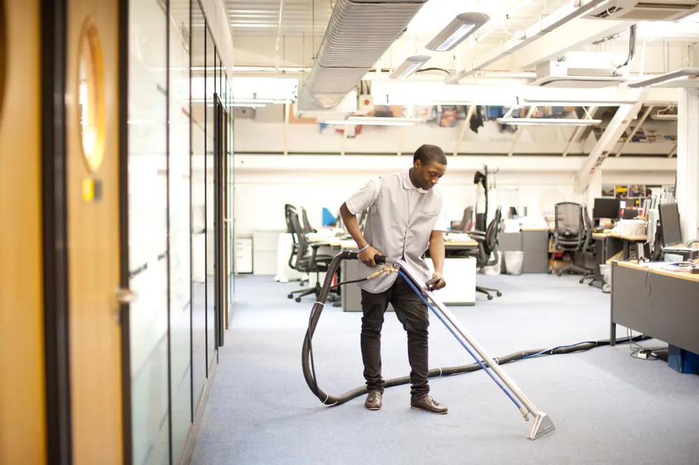 Man hoovering an office floor with a commercial hoover used by specialists