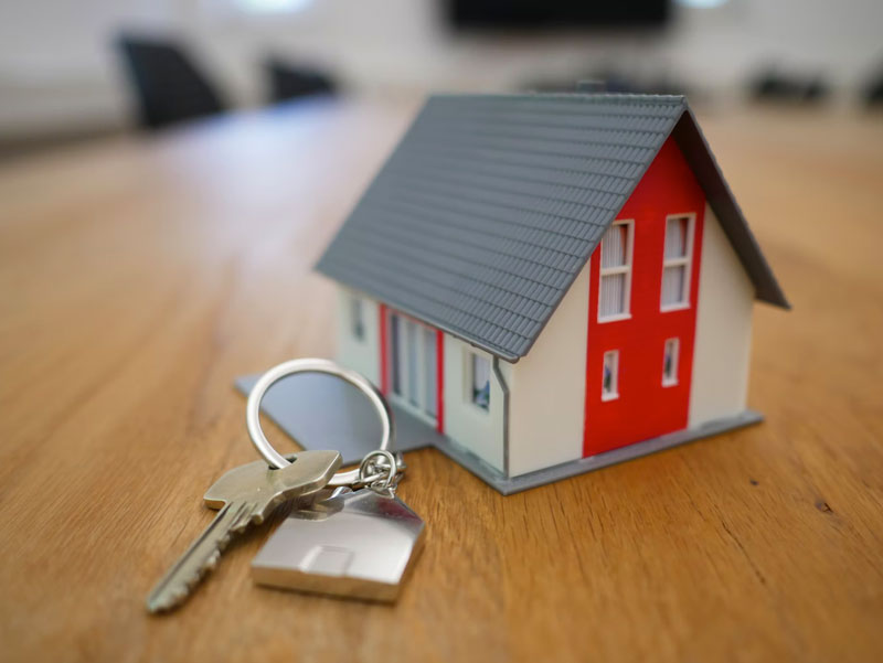 house keys next to a toy house on a wooden table