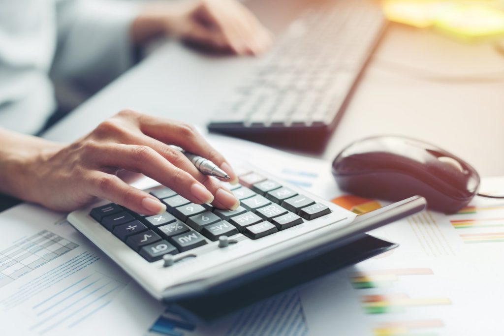 Close up hand of business woman accountant or banker making calculations. Savings, finances and economy audit debt concept